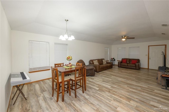 dining space with ceiling fan with notable chandelier, lofted ceiling, and light hardwood / wood-style flooring