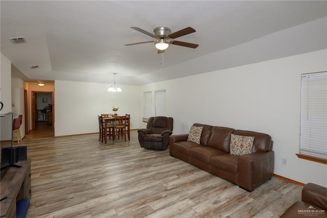 living room with ceiling fan with notable chandelier and light hardwood / wood-style floors