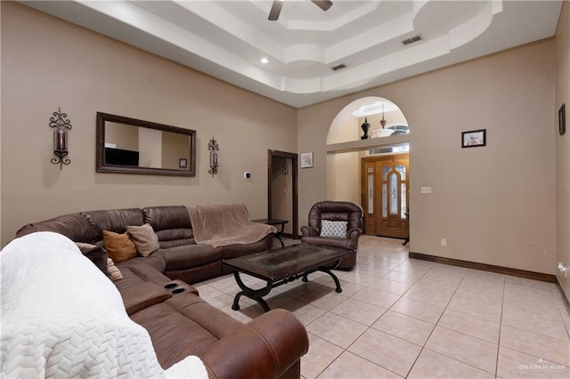 living area featuring light tile patterned floors, a raised ceiling, visible vents, a high ceiling, and baseboards