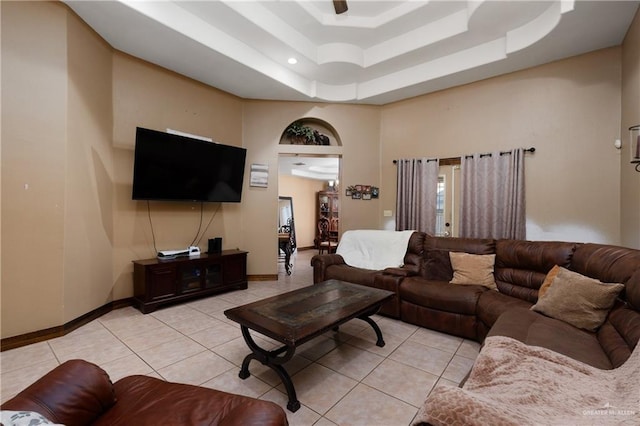 living room featuring a raised ceiling, a towering ceiling, baseboards, and light tile patterned floors