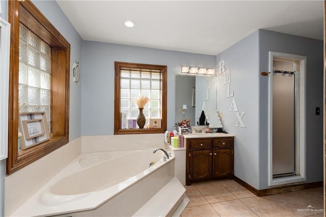 full bath featuring tile patterned flooring, a garden tub, vanity, baseboards, and a shower stall