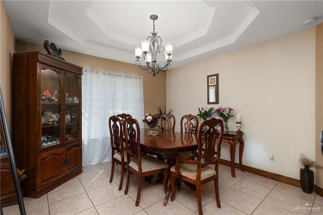 dining area featuring baseboards, a tray ceiling, a chandelier, and light tile patterned flooring