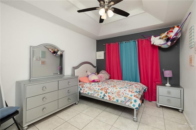 tiled bedroom featuring ceiling fan and a tray ceiling