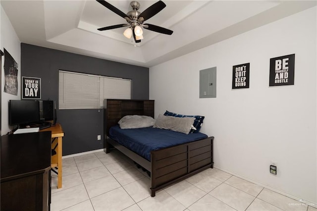 tiled bedroom featuring ceiling fan, a tray ceiling, and electric panel