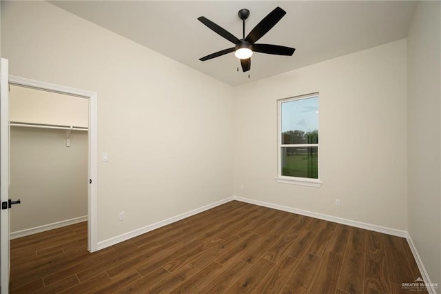 unfurnished bedroom featuring a closet, a walk in closet, dark hardwood / wood-style floors, and ceiling fan