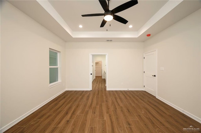 unfurnished room featuring dark hardwood / wood-style flooring, a raised ceiling, and ceiling fan