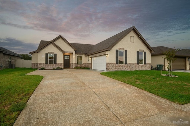 view of front facade featuring central AC, a garage, and a lawn