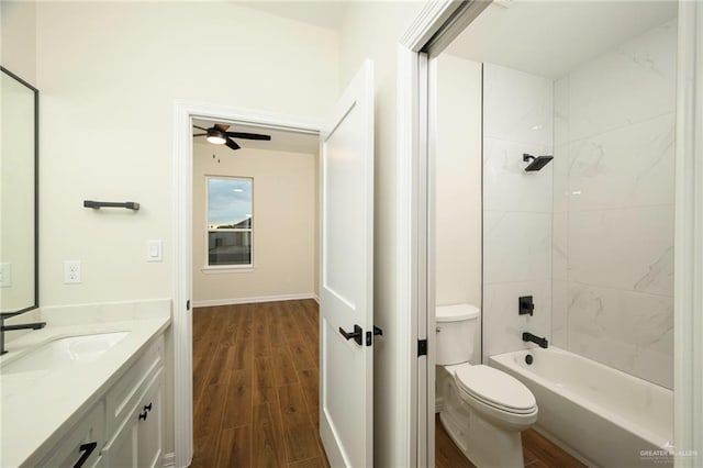 full bathroom featuring vanity, tiled shower / bath combo, ceiling fan, hardwood / wood-style floors, and toilet