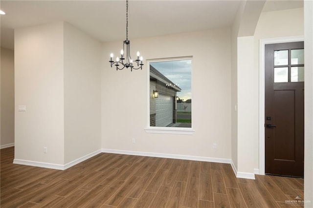 unfurnished dining area featuring dark wood-type flooring and a notable chandelier