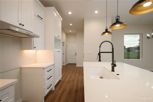 kitchen featuring dark hardwood / wood-style flooring, white cabinets, hanging light fixtures, and sink