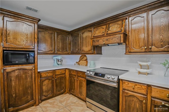 315 Oregano St, Edinburg, TX 78541 - kitchen with stainless steel electric stove, black microwave, light tile patterned floors, light countertops, and custom exhaust hood
