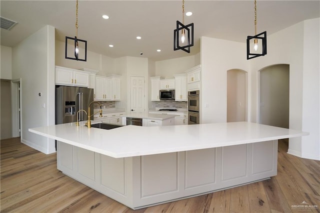 kitchen featuring sink, tasteful backsplash, appliances with stainless steel finishes, pendant lighting, and a large island