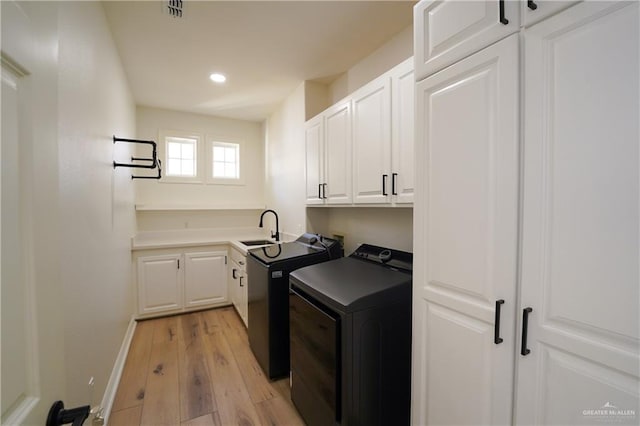 washroom featuring cabinets, washer / clothes dryer, sink, and light hardwood / wood-style flooring