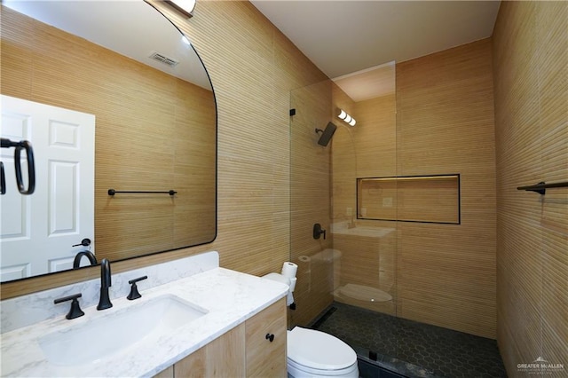 bathroom featuring a tile shower, vanity, and toilet