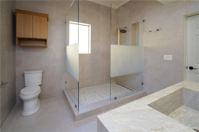 bathroom with sink, tile walls, a tile shower, tile patterned floors, and toilet