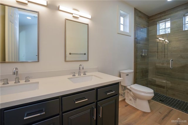 bathroom featuring wood-type flooring, toilet, a shower with shower door, and vanity