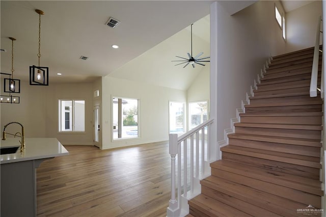 staircase featuring sink, hardwood / wood-style flooring, high vaulted ceiling, and ceiling fan