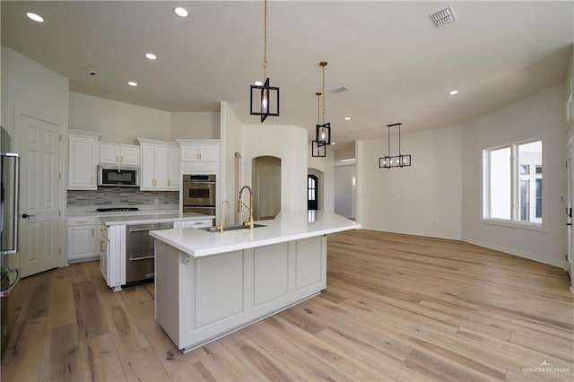 kitchen featuring sink, hanging light fixtures, appliances with stainless steel finishes, a large island, and white cabinets