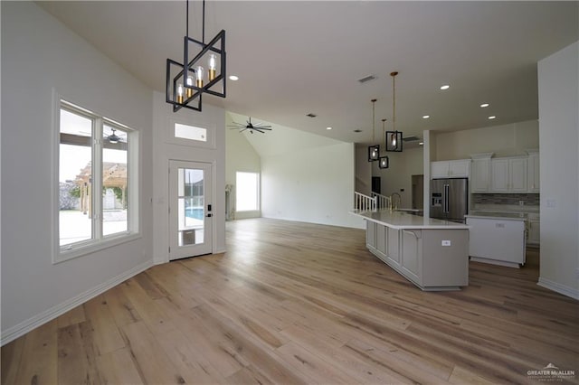 kitchen featuring white cabinetry, decorative light fixtures, high end refrigerator, and an island with sink