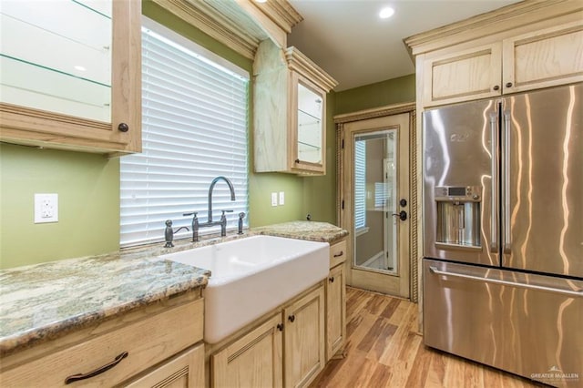 kitchen with light stone countertops, sink, light brown cabinets, stainless steel refrigerator with ice dispenser, and light hardwood / wood-style floors