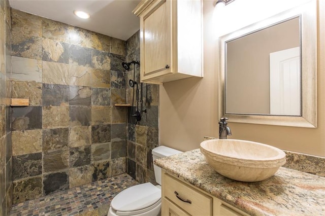 bathroom with a tile shower, vanity, and toilet