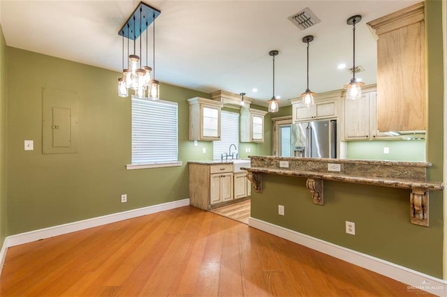 kitchen with stainless steel fridge, electric panel, light hardwood / wood-style floors, and decorative light fixtures