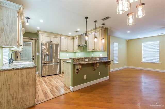 kitchen with stainless steel fridge, light hardwood / wood-style floors, and hanging light fixtures