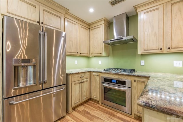 kitchen featuring light stone countertops, light brown cabinetry, light wood-type flooring, wall chimney exhaust hood, and stainless steel appliances