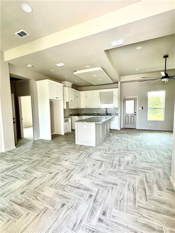 kitchen with white cabinets, ceiling fan, and a kitchen island