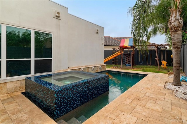 view of pool featuring a patio, a playground, and an in ground hot tub