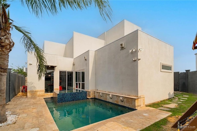 rear view of house featuring a fenced in pool and a patio area