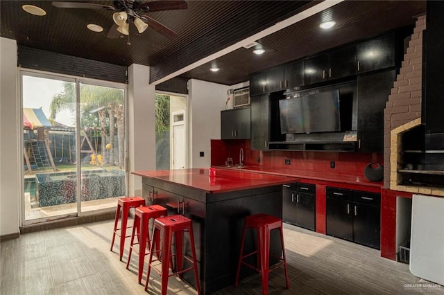 kitchen with ceiling fan, a kitchen island, sink, and a kitchen bar