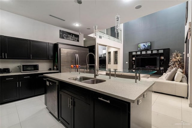 kitchen with built in fridge, black dishwasher, sink, a kitchen island with sink, and light tile patterned floors