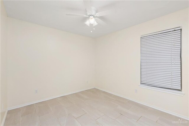 empty room with a ceiling fan and baseboards