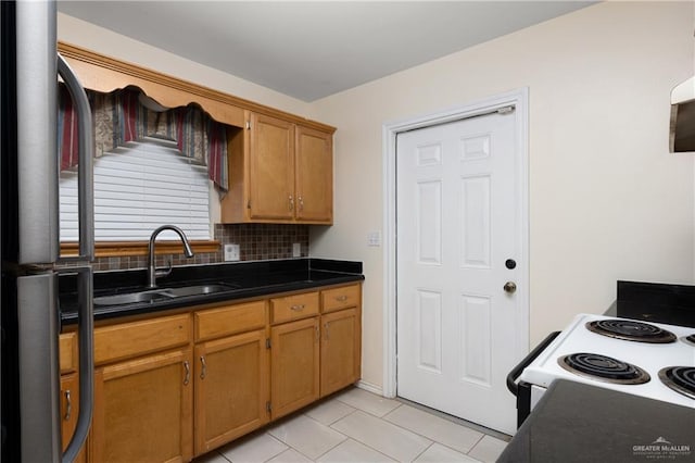 kitchen featuring a sink, freestanding refrigerator, electric range oven, tasteful backsplash, and dark countertops