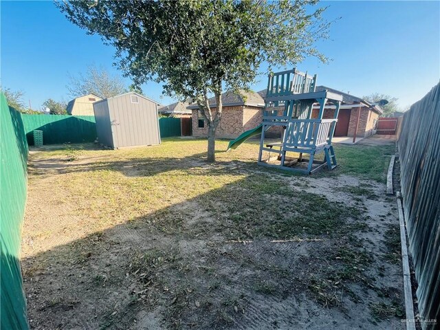 view of play area with an outbuilding, a fenced backyard, a yard, and a storage unit