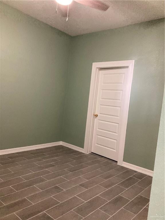 spare room featuring a textured ceiling, ceiling fan, and dark hardwood / wood-style floors