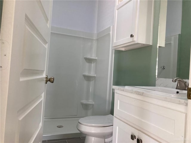 bathroom featuring tile patterned flooring, vanity, toilet, and a shower