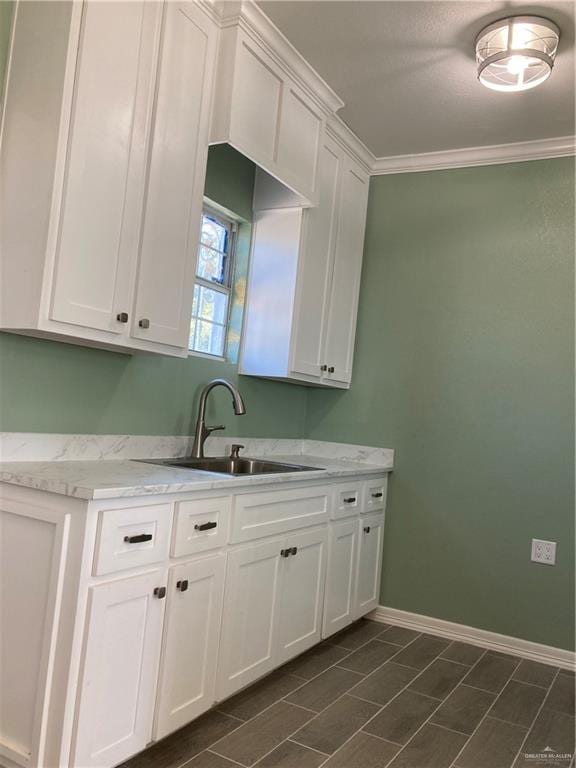 kitchen featuring white cabinetry, sink, and ornamental molding