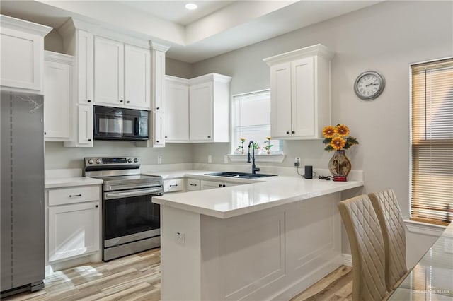 kitchen with a healthy amount of sunlight, white cabinetry, light hardwood / wood-style flooring, and stainless steel appliances