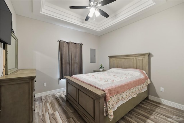 bedroom featuring electric panel, a tray ceiling, ceiling fan, and dark hardwood / wood-style floors