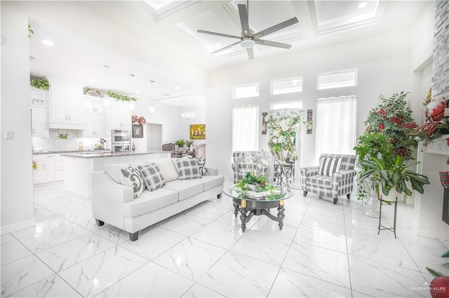 living room with beamed ceiling, a high ceiling, ceiling fan, and coffered ceiling