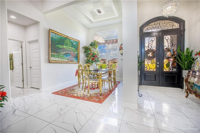 foyer entrance featuring a chandelier, a towering ceiling, and french doors