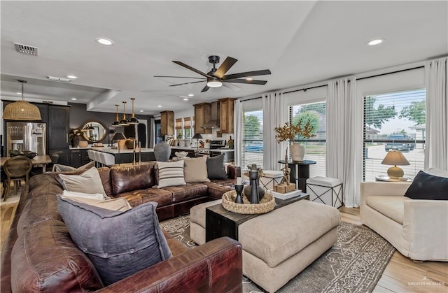 living room with ceiling fan, a wealth of natural light, and light hardwood / wood-style flooring