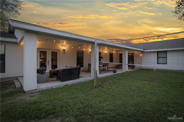 back house at dusk with a yard and a patio