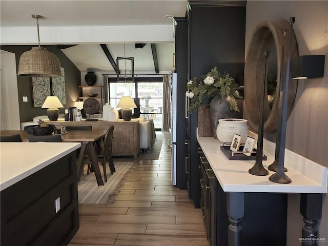 kitchen featuring vaulted ceiling with beams, hanging light fixtures, and light wood-type flooring