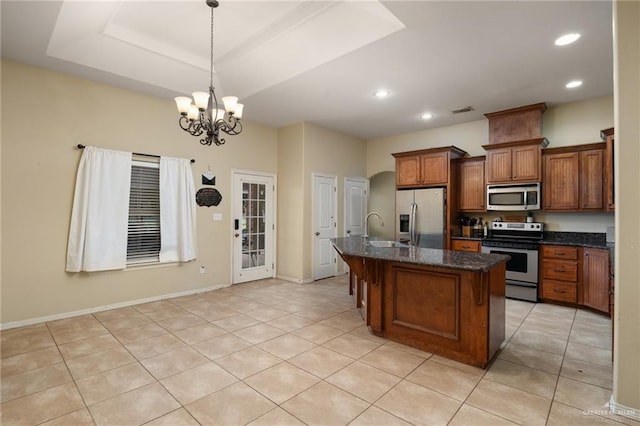 kitchen featuring sink, hanging light fixtures, an island with sink, appliances with stainless steel finishes, and a notable chandelier