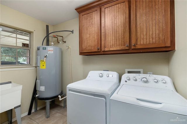 laundry area with cabinets, sink, water heater, light tile patterned flooring, and washing machine and clothes dryer