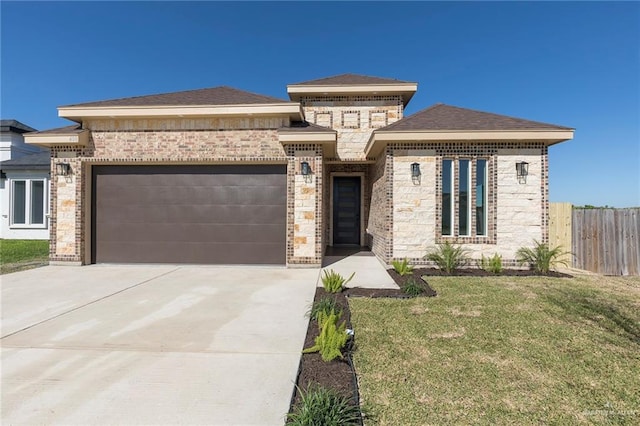 prairie-style house featuring a garage, brick siding, driveway, and fence