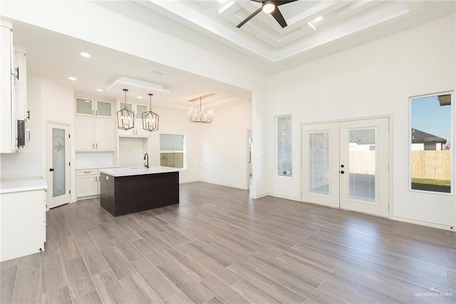 kitchen with dark wood-type flooring, open floor plan, a center island with sink, light countertops, and french doors